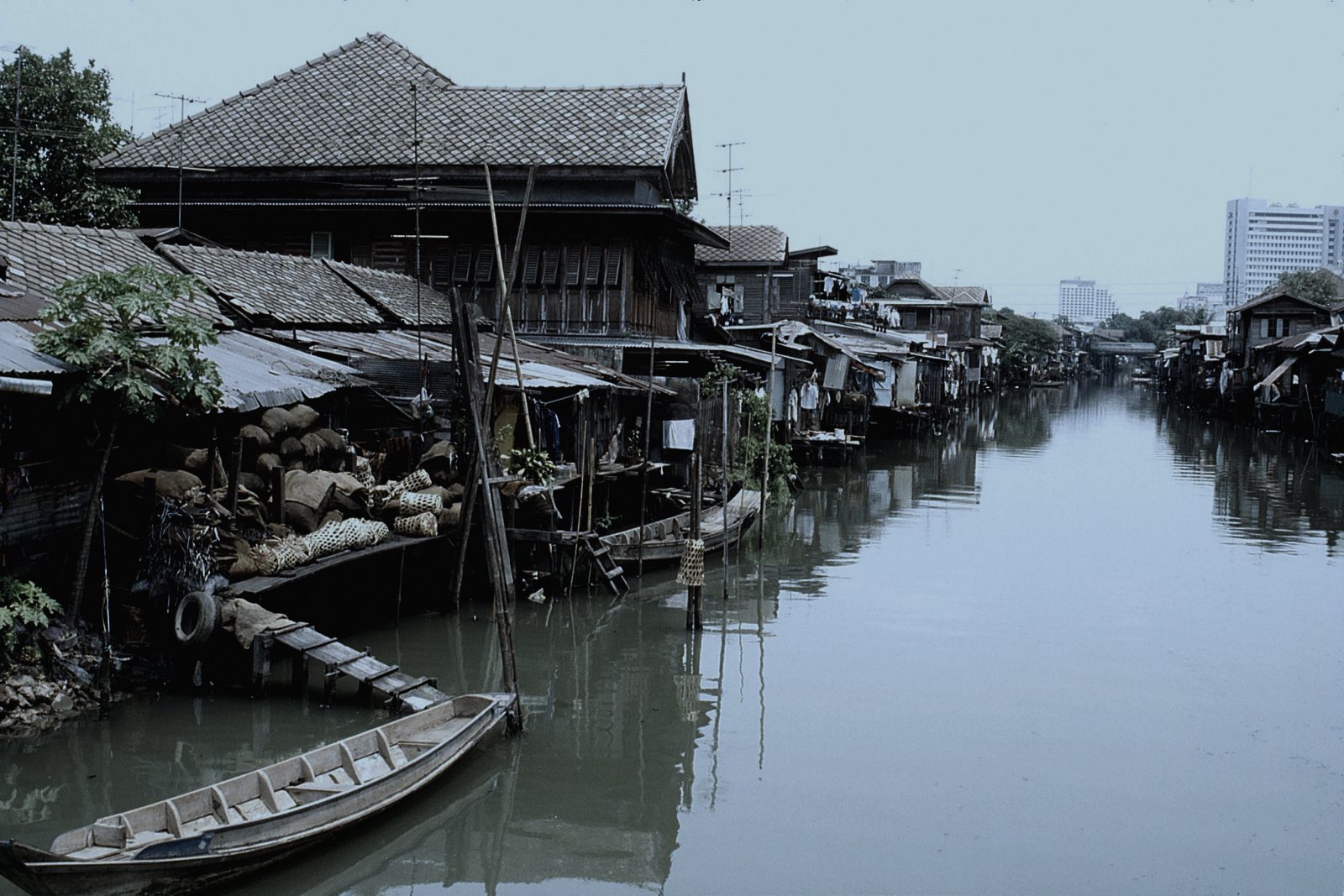 ตั้งอยู่ริมคลองในหมู่บ้านชานเมืองภาคกลาง เพราะราวตากผ้าแบบไม้ไผ่และวิถีชีวิตริมคลองยังพบได้จริงในพื้นที่แบบนี้